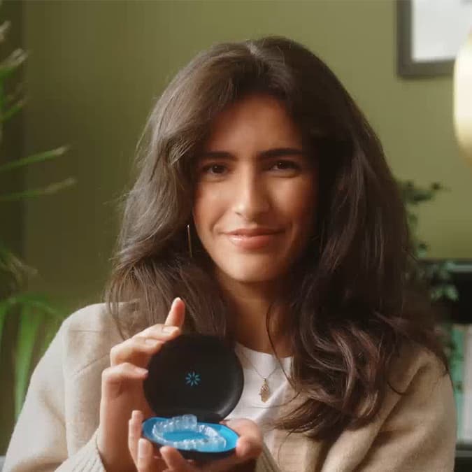 Young woman smiling and showing her Invisalign® aligners in their case